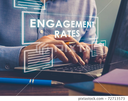 Engagement Rates sign on the screen. A man works on a laptop. 72713573