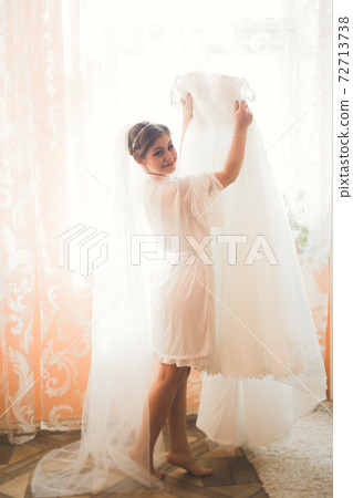 Beautiful bride wearing fashion wedding dress with feathers with luxury delight make-up and hairstyle, studio indoor photo shoot Beautiful bride wearing fashion wedding dress with feathers with luxury delight make-up and hairstyle, studio indoor photo shoot 72713738