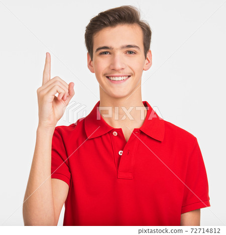Portrait of happy young man pointing up buy finger, isolated over white background. Photo of smiling Handsome white guy in a red shirt showing index finger. Male person with an idea gesture. Portrait of happy young man pointing up buy finger, isolated over white background. Photo of smiling Handsome white guy in a red shirt showing index finger. Male person with an idea gesture. 72714812