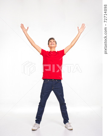 Photo of full length portrait of young happy smiling man with lifted hands up, isolated on a white background. Attractive teenage in a red shirt and dark blue jeans with raised hands. Photo of full length portrait of young happy smiling man with lifted hands up, isolated on a white background. Attractive teenage in a red shirt and dark blue jeans with raised hands. 72714898