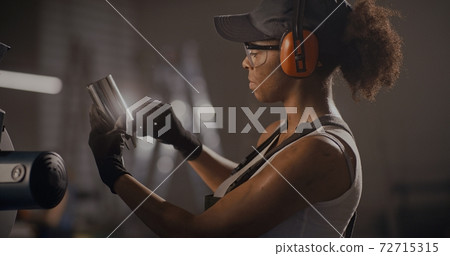 Black female worker of factory measuring metal pipe piece Black female worker of factory measuring metal pipe piece 72715315