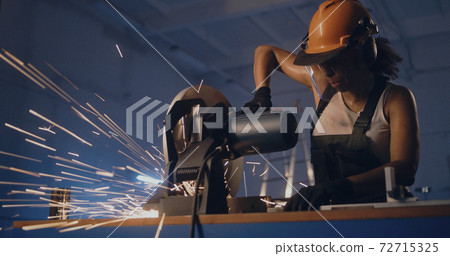 Professional woman at workbench with metal cutting saw Professional woman at workbench with metal cutting saw 72715325