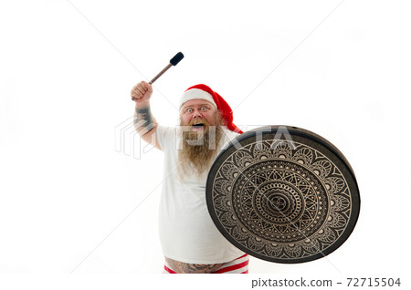 Isolated portrait on a white background of an overweigh shaman man in Santa Claus hat dancing with a shaman tambourine Isolated portrait on a white background of an overweigh shaman man in Santa Claus hat dancing with a shaman tambourine 72715504