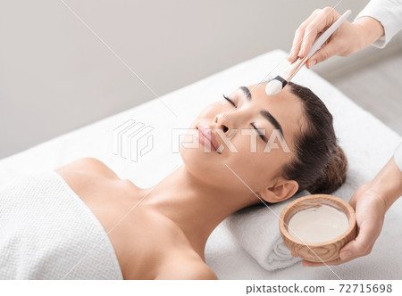 Beauty Treatment. Beautician applying clay mask to asian woman at spa salon 72715698