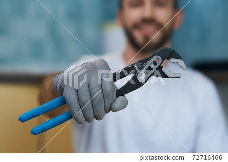 Necessary hand tool. Close up shot of hand of young repairman holding a pipe wrench 72716466