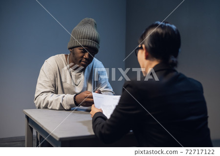 A beautiful girl investigator in an elegant suit asks a black criminal to cooperate with the investigation and sign a confession. A beautiful girl investigator in an elegant suit asks a black criminal to cooperate with the investigation and sign a confession. 72717122