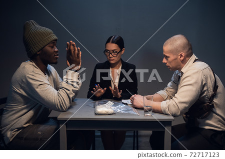 A pretty girl lawyer is present at the interrogation of a black criminal detained with drugs on the street 72717123
