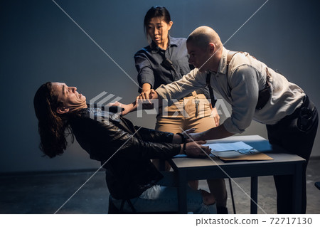 Violence by a police officer against a suspect in an interrogation room. An officer threatens a man with a weapon in the presence of a witness. Violence by a police officer against a suspect in an interrogation room. An officer threatens a man with a weapon in the presence of a witness. 72717130
