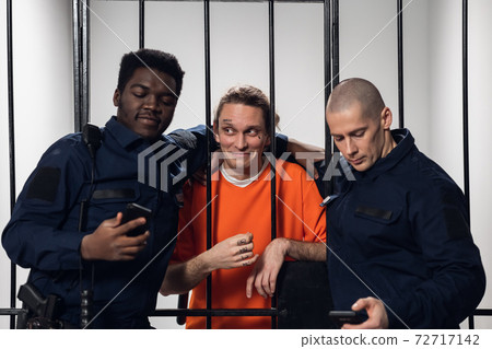A prisoner with tattoos on his face takes a selfie with his fellow prison guards on a smartphone. A prisoner with tattoos on his face takes a selfie with his fellow prison guards on a smartphone. 72717142