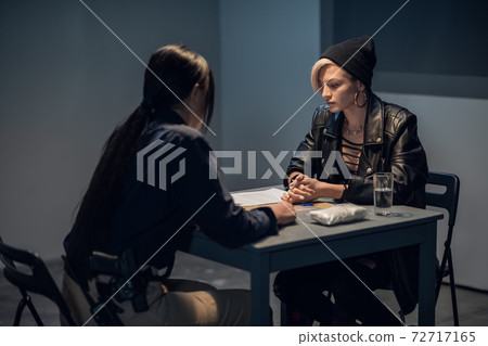 A young police officer is interrogating a girl suspected of distributing drugs A young police officer is interrogating a girl suspected of distributing drugs 72717165