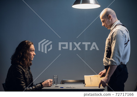 A police officer introduces the suspect to the details of the case A police officer introduces the suspect to the details of the case 72717166