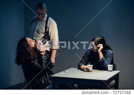 A suspect in a police station laughs madly during an interrogation conducted by investigators A suspect in a police station laughs madly during an interrogation conducted by investigators 72717168