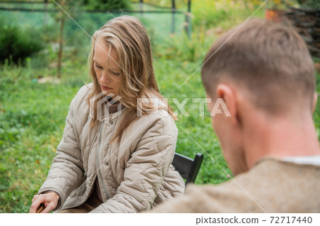 Young dad and mom are cutting vegetables and preparing for a family picnic in the courtyard of their own country house. 72717440