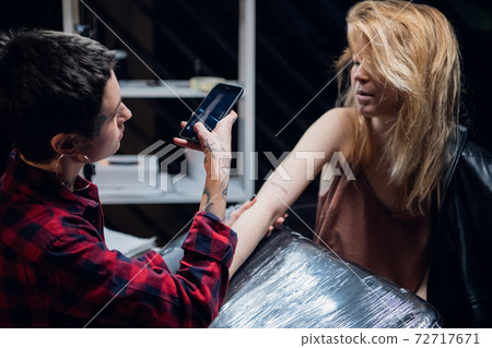 Tattoo artist a young girl made her first tattoo to a client and takes the result for memory 72717671