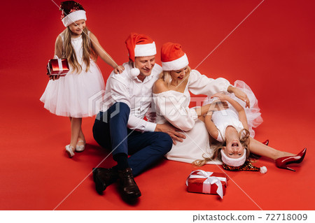 Portrait of a happy family in a Christmas hat on a red background 72718009