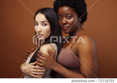 young pretty asian and afro woman posing cheerful together on brown background, lifestyle diverse nationality people concept 72718753