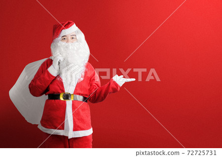 Asian man in Santa costume with an open hand carrying gift bag Asian man in Santa costume with an open hand carrying gift bag 72725731