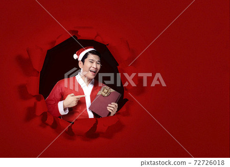 Asian man in Santa costume standing and holding the gift box Asian man in Santa costume standing and holding the gift box 72726018