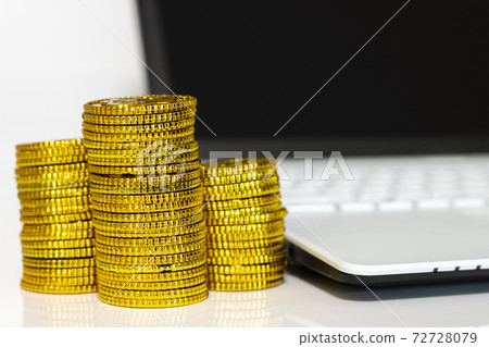 Stacked gold coins and laptops, business image 72728079