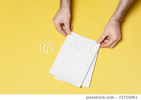 Male hand holding a closed book-catalog with blank cover on yellow background mock-up series Male hand holding a closed book-catalog with blank cover on yellow background mock-up series 72728961