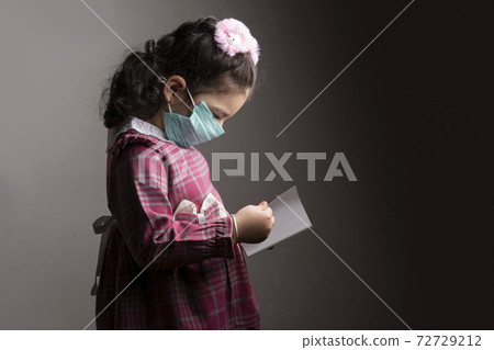 A little girl with protection hospital mask studying a book A little girl with protection hospital mask studying a book 72729212