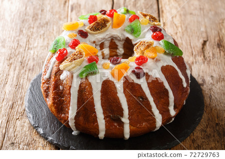 Festive pound cake with raisins, dried apricots, dried cherries, kiwi and cranberries and icing close-up on a board. horizontal 72729763