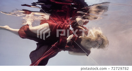 A woman in a red dress underwater as if floating in weightlessness A woman in a red dress underwater as if floating in weightlessness 72729782