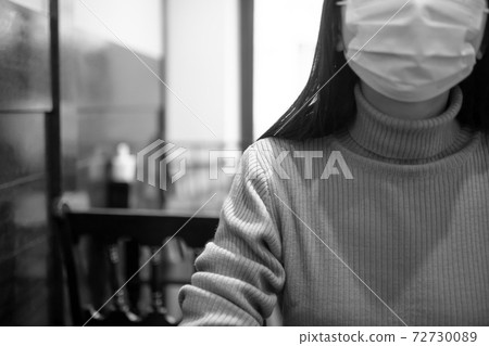 A woman wearing a mask at a cafe [monochrome] 72730089