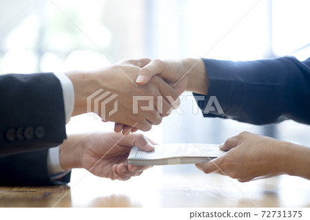 Businessman shake hand with officer and hold the cash Businessman shake hand with officer and hold the cash 72731375