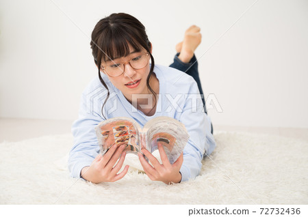 A woman reading a comic while lying down 72732436