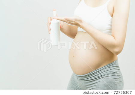 Selective focus of pregnant woman using moisture cream to prevent stretch marks on her belly over gray background with copy space. Skincare,preparation and expectation concept. 72736367