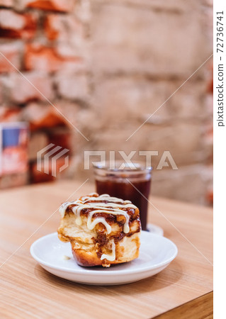 A plate of mini cinnamon rolls and a cup of black coffee 72736741