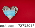 White heart with a blue face mask on a red background. Concept of a Valentines day during Coronavirus or Covid pandemic.. 72738037