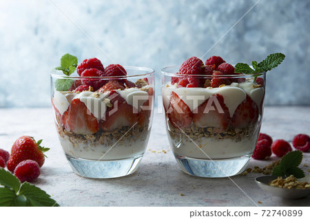 Two glasse with layered yogurt, granolla and fruits, strawberry ans raspberry. Healthy breakfast. 72740899
