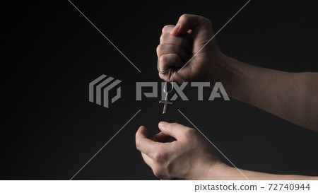Cross or crucifix pendant and necklace in man hand on black color background in studio which represent praying for god or jesus and thank gods for giving peaceful and faithful to people. silver cross. 72740944