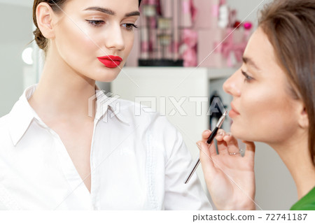 Makeup artist applies lipstick. 72741187