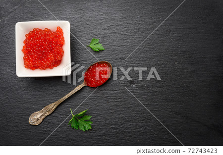 fresh grained red chum salmon caviar in a white ceramic bowl on a black slate stone background fresh grained red chum salmon caviar in a white ceramic bowl on a black slate stone background 72743423