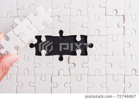 hand-holding last piece white paper jigsaw puzzle game last pieces put to place 72746067