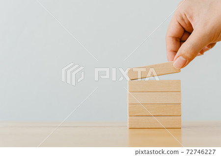 Hand arranging wood block stacking on top with wooden table 72746227