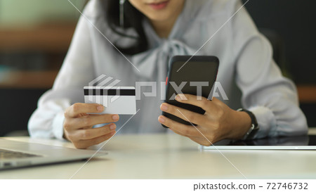 Businesswoman using smartphone and credit card to online payment in office room 72746732
