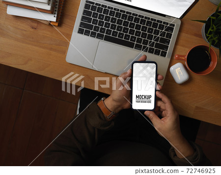 Male hand using smartphone on worktable with laptop and supplies Male hand using smartphone on worktable with laptop and supplies 72746925