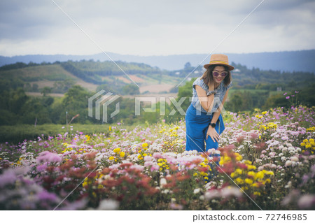 beautiful woman standing in blooming flower garden 72746985