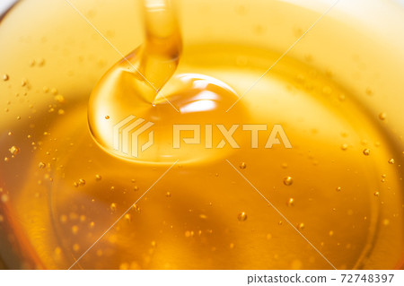 Honey syrup being poured into a glass bowl photo material 72748397