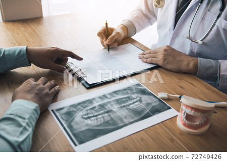 Dentists are discussing dental problems at report x-ray image for patients. 72749426