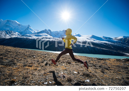 Woman trail runner cross country running in winter mountains 72750207
