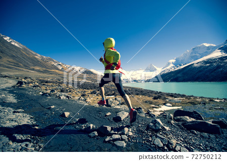 Woman trail runner cross country running in winter mountains Woman trail runner cross country running in winter mountains 72750212