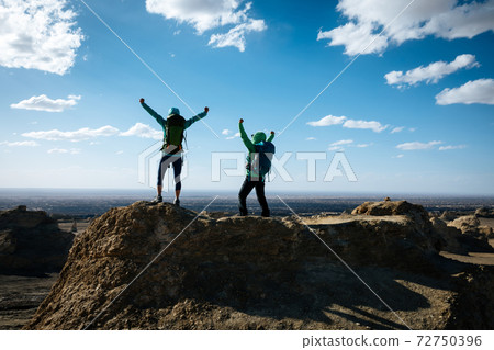 Two women backpackers hiking on sand desert Two women backpackers hiking on sand desert 72750396