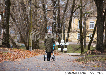 Woman walks with baby stroller Woman walks with baby stroller 72757972