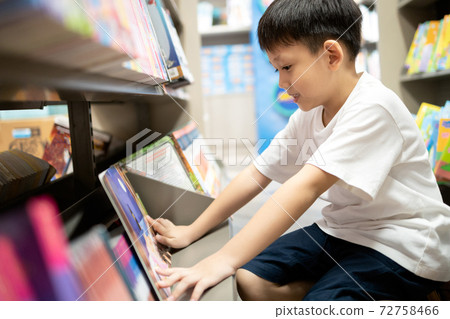 Asian little child reading a cartoon from favorite comic book on bookshelf at bookstore,happy kid boy enjoying learning in school library,brain development,education,reading skills in childhood Asian little child reading a cartoon from favorite comic book on bookshelf at bookstore,happy kid boy enjoying learning in school library,brain development,education,reading skills in childhood 72758466