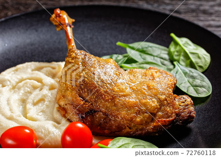 Duck confit with parsnip puree on a black plate 72760118